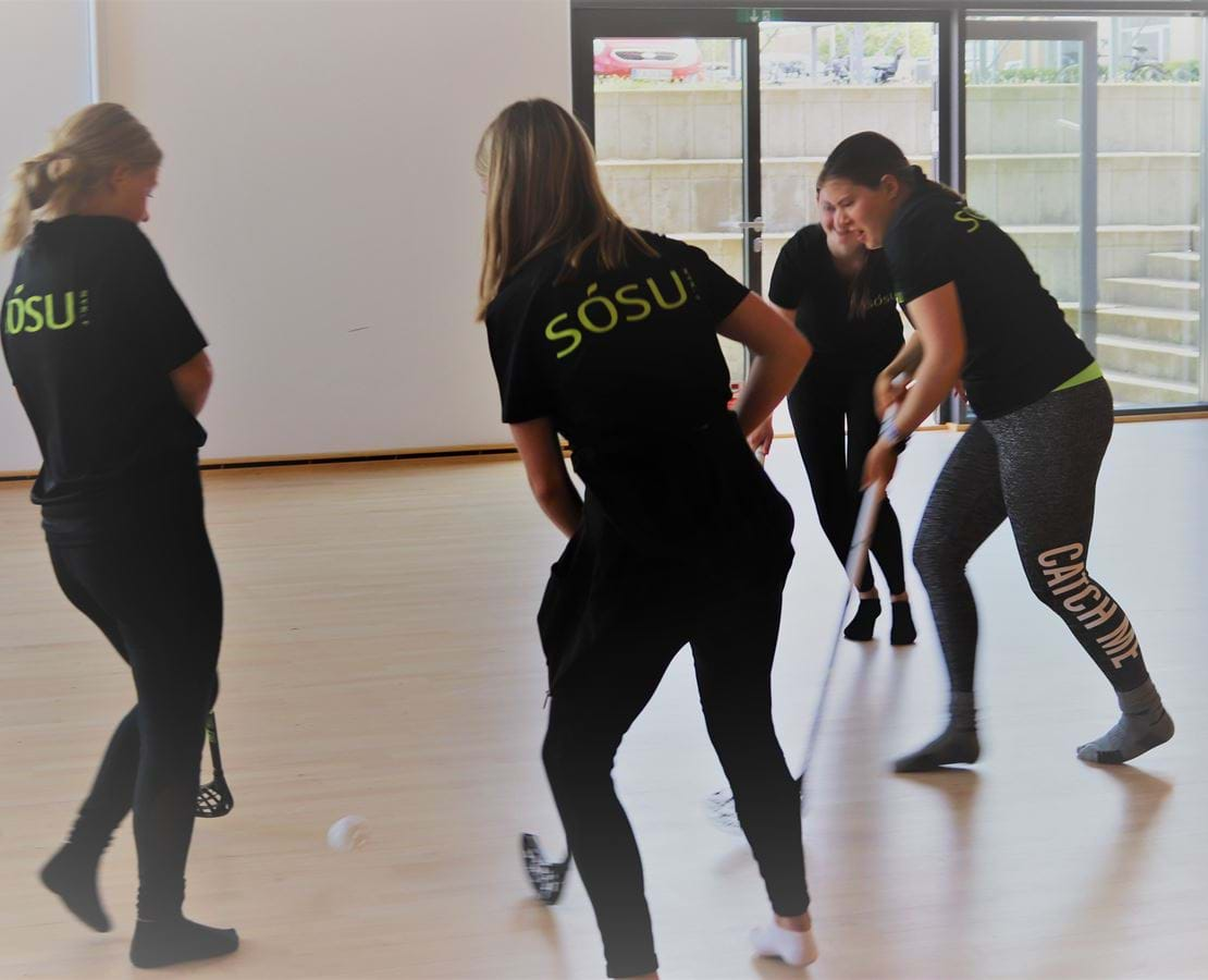 Unge mennesker spiller hockey indendørs i skolens Multisal