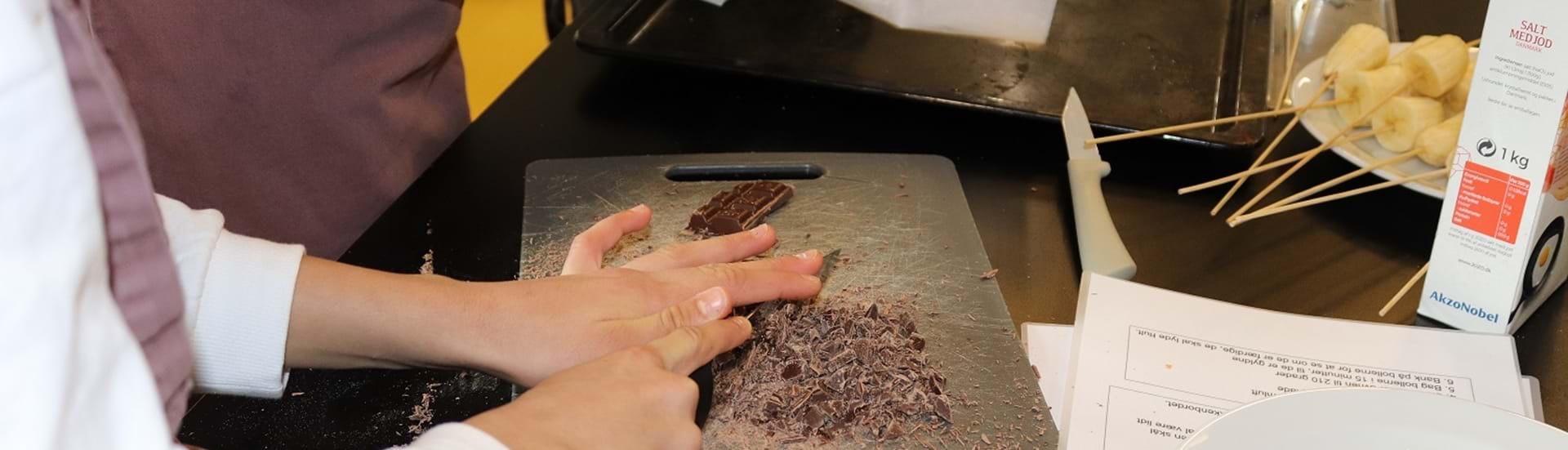 Hakker chokolade på et skærebrædt.