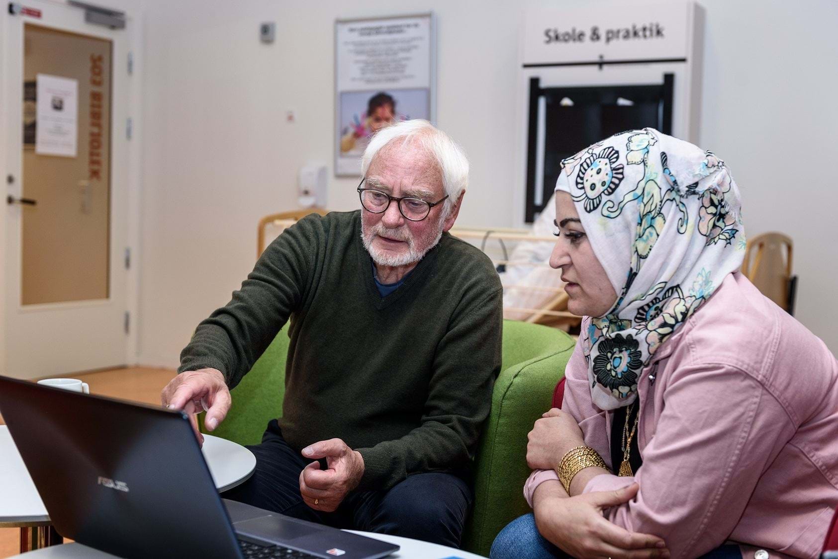 To voksne mennesker sidder i dialog og ser på skærmen på en laptop.