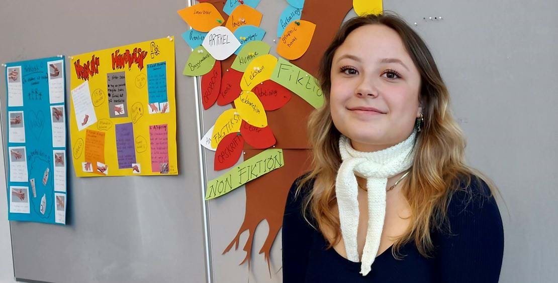 Bjørk Arvidsen er en ung kvinde, der kigger smilende ind i kameraet. Hun har sort tøj på og et hvidt, strikket tørklæde tæt om halsen.