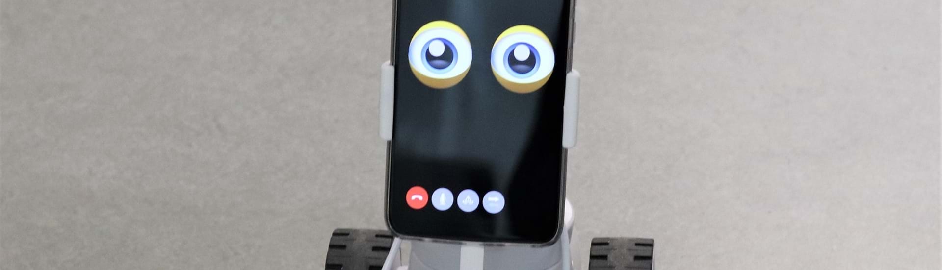 En lille robot med hjul på kigger ind i kameraet med sine tegnede øjne.
