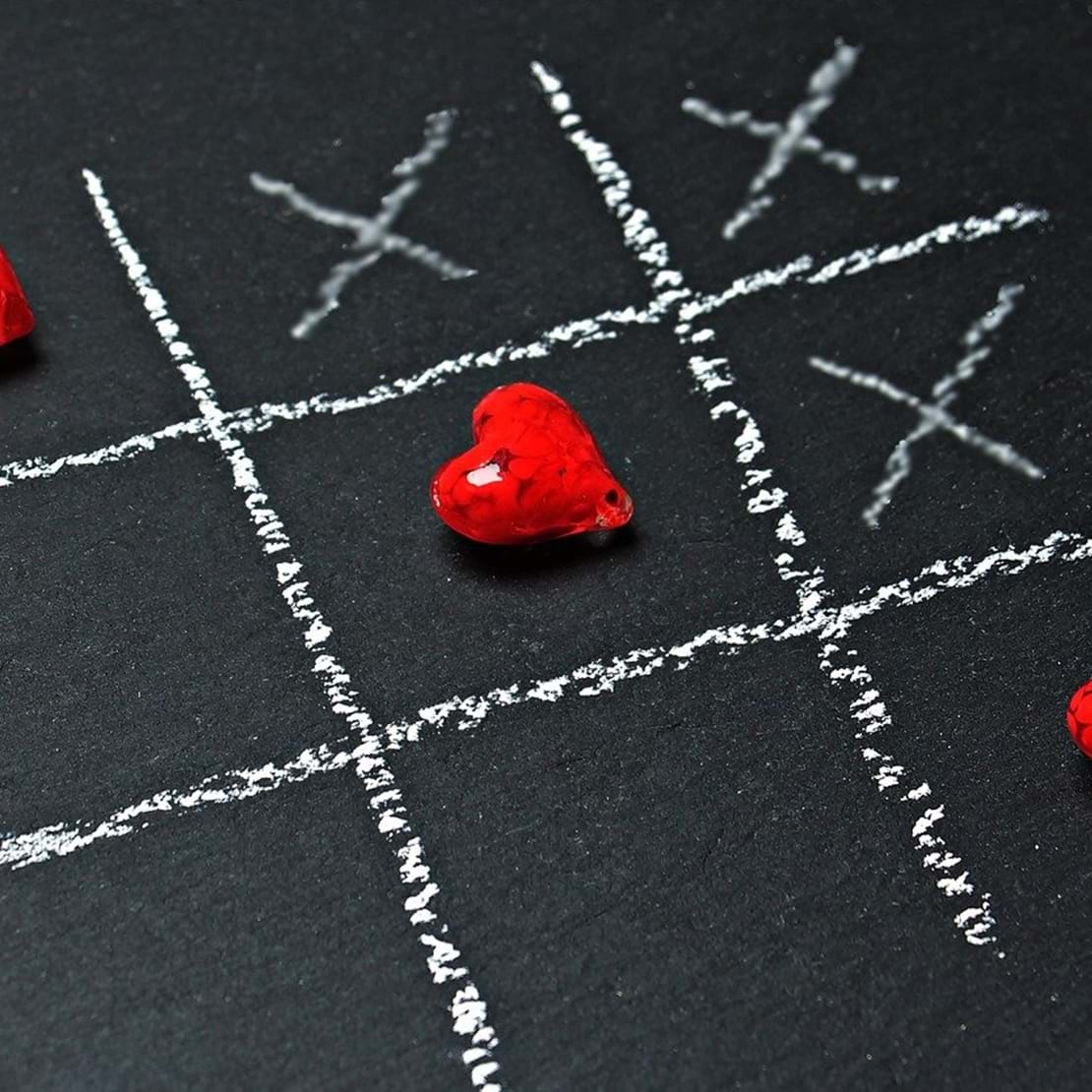 Tre på stribe hjerter i et spil kryds og bille tegnet på med kridt på en tavle.