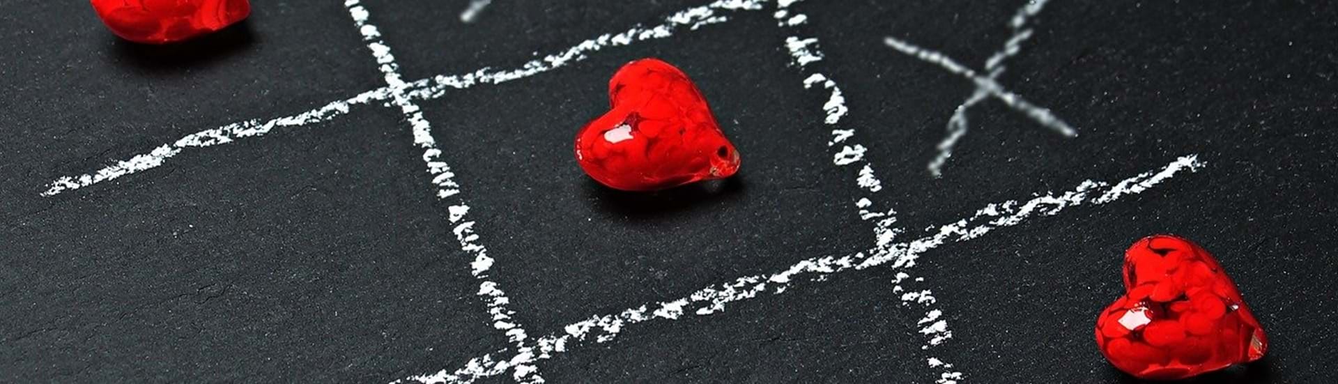 Tre på stribe hjerter i et spil kryds og bille tegnet på med kridt på en tavle.