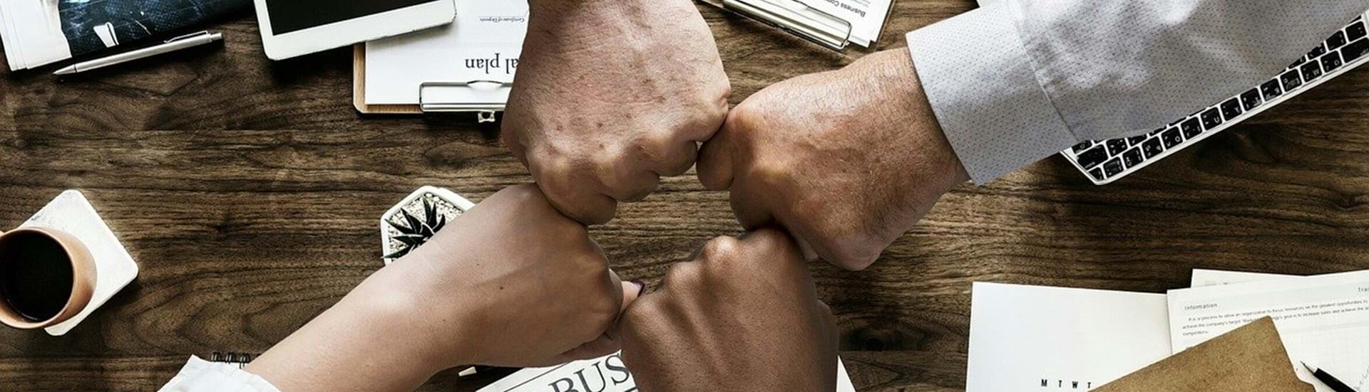 Fire knyttede hænder mødes i et fælles 'fist bump'
