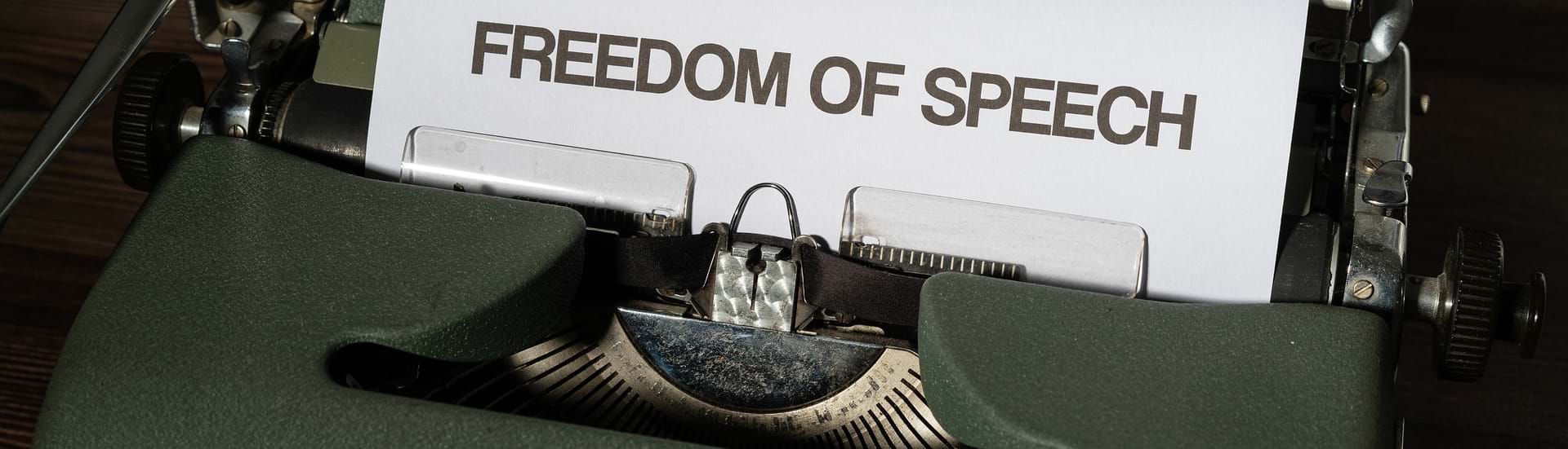 En skrivemaskine med et stykke papir i hvor der der skrevet freedom of speech (ytringsfrihed).