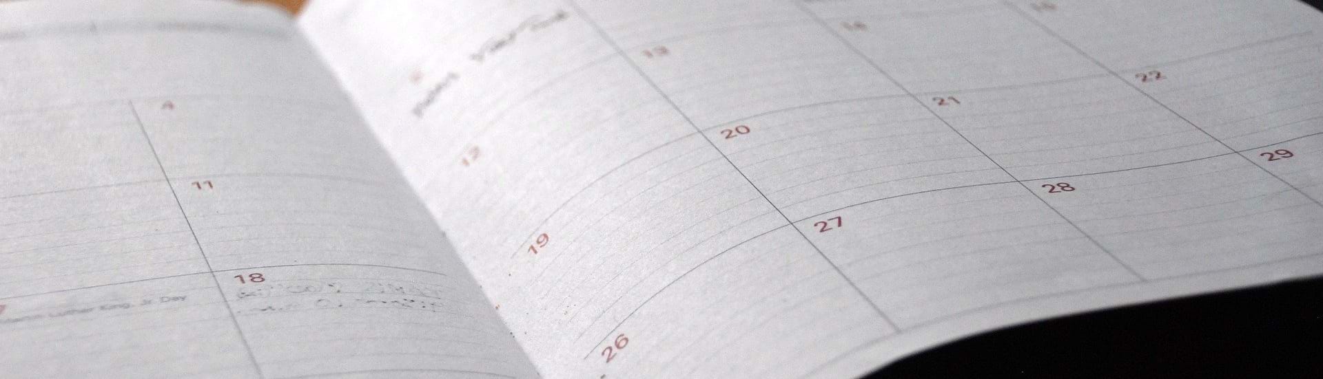 En papirkalender ligger opslået på et bord.